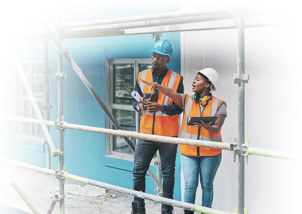 Two construction workers standing on scaffolding and talking.