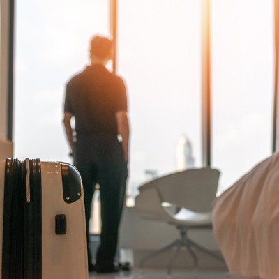 Man in hotel room with a suitcase.